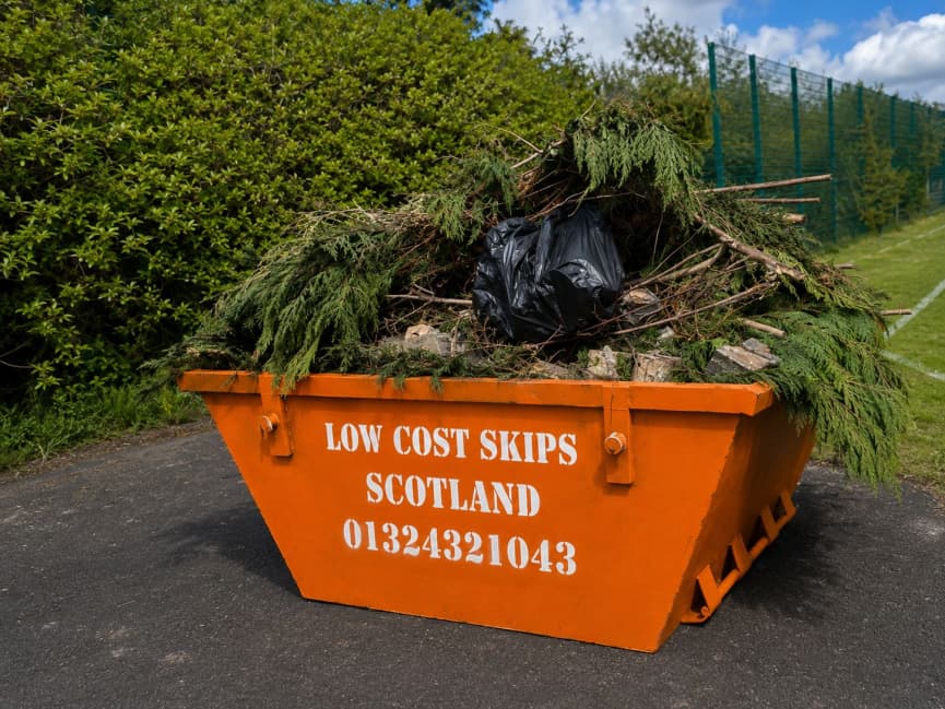 Low Cost Skips Scotland orange branded skip full of garden waste